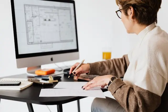 mujer frente a una laptop con planos digitales